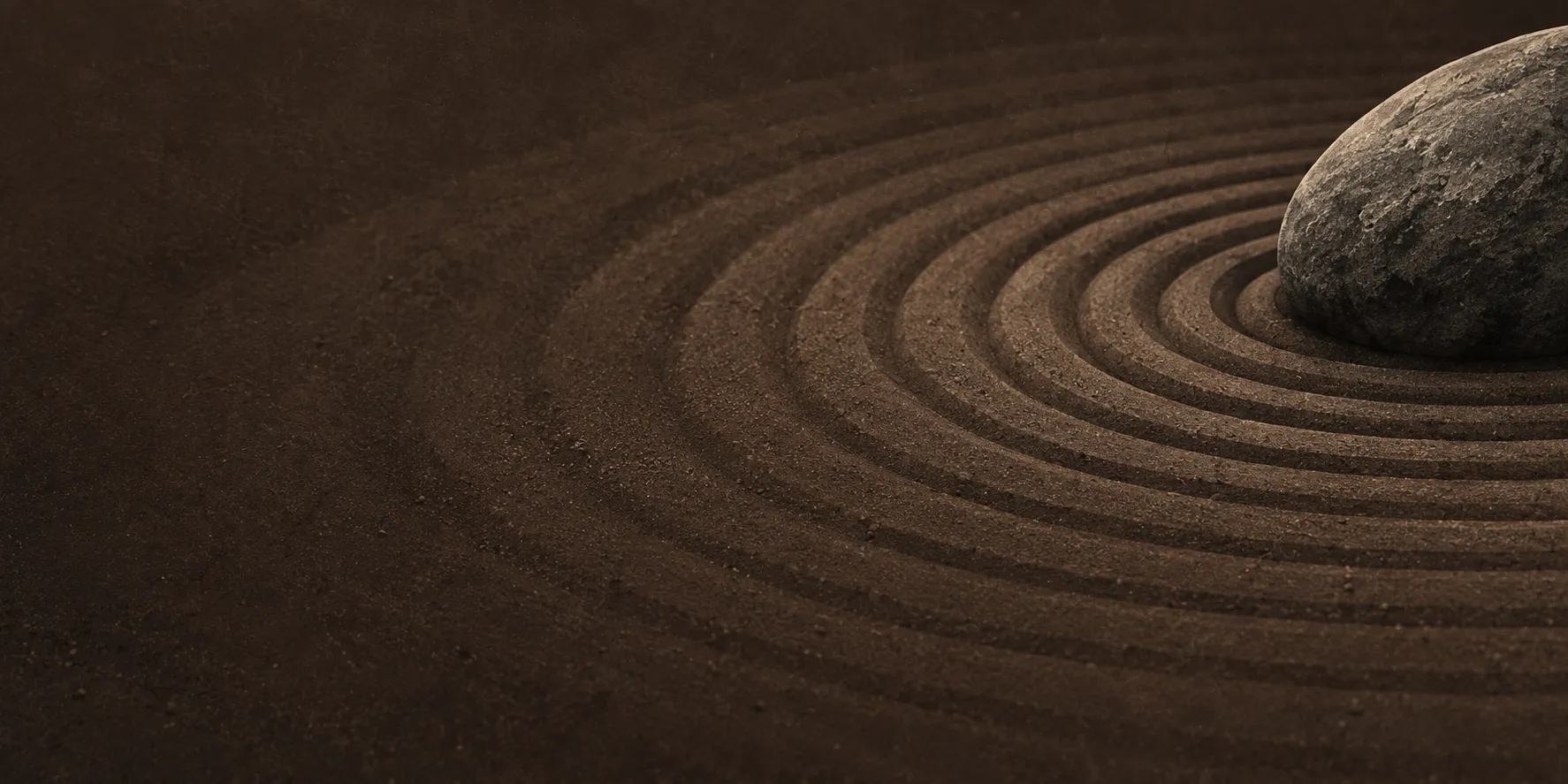 A single stone set in raked sand, the rings drawn around it.